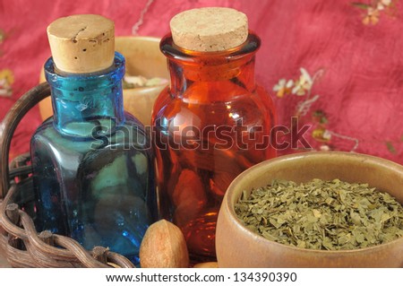 Vintage medical bottles and a mix of dry herbs on red runner