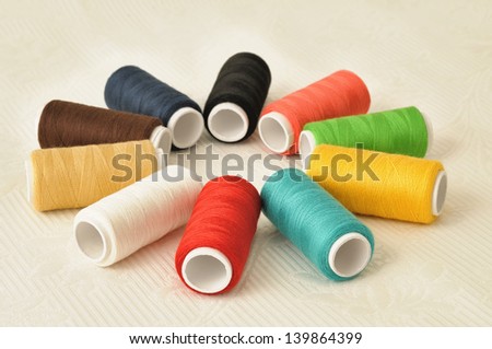 Spools of threads of different colors on light table cloth