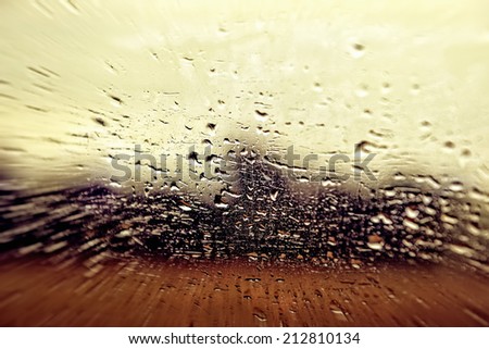 View from a car window during rain with smashed droplets as a weather background. Tone filters applied