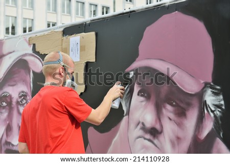 BRUSSELS, BELGIUM-AUGUST 29, 2014: Unidentified graffitist paints on a temporary wall installed in Mont des Arts parc in center of Brussels