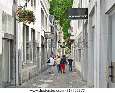 MAASTRICHT, NETHERLANDS-JULY 07, 2014: Tourists walking by narrow street in historical center of the city. Maastricht is a capital of Limburg province and one of popular tourist destinations