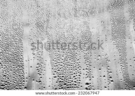 Rain drops created a natural pattern on window glass. Conversion to black and white, very detailed reflections