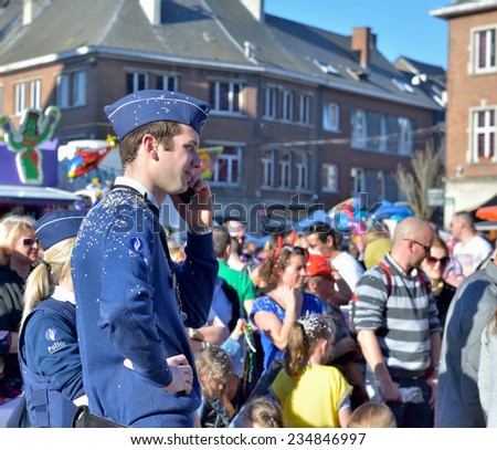 NIVELLES, BELGIUM-MARCH 03, 2014: Police agent covered by confetti and artificial snow during parade of yearly carnival in Nivelles