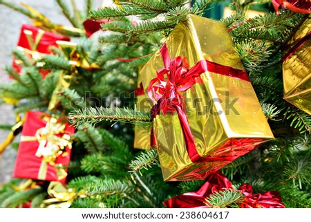 Golden foil gift boxes on street Christmas fir with rain drops