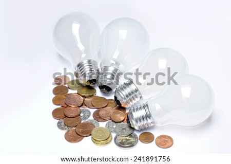 incandescent lamps and coins on a light table as concept of energy economy