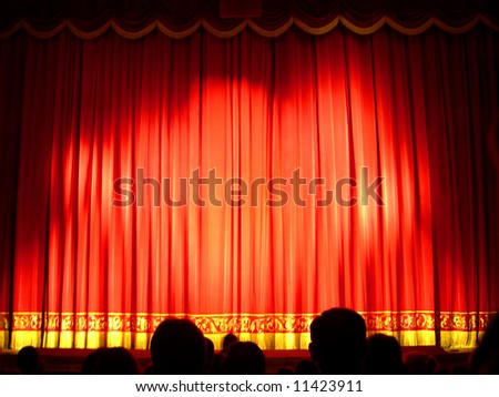 Closed red Theater stage curtain with dark silhouettes of people