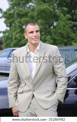 Young businessman outside of office with cars on background