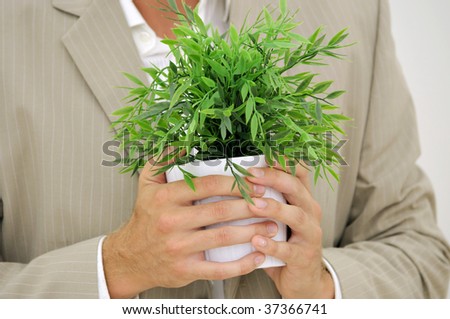Man in office suit with green plant in hands as 