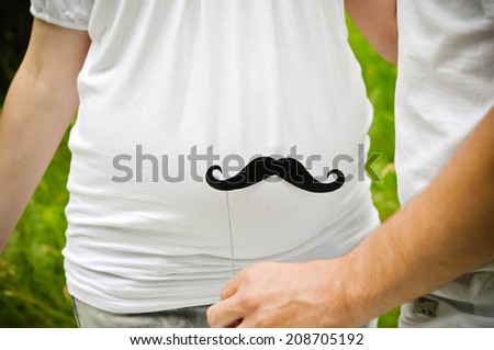 Happy and young pregnant couple outdoors with mustache near belly