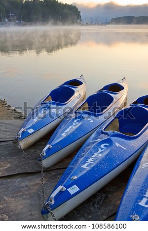 Kayak boats at the lake shore in morning fog