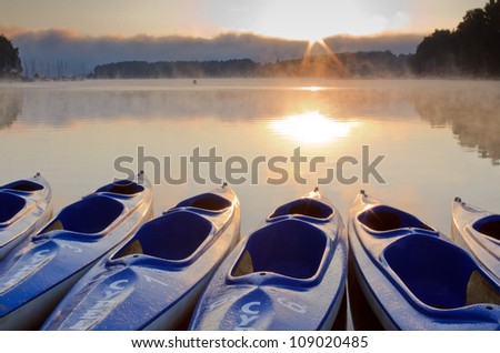 Kayak boats at lake shore in morning fog
