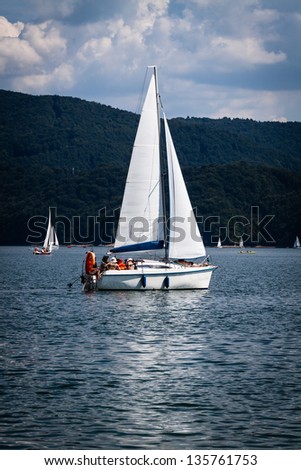 people sail on boat ship at lake before storm