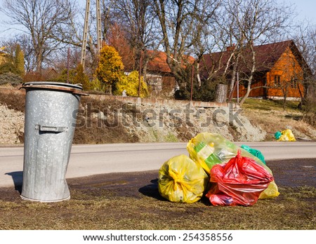 Colorful plastic bags and metal rubbish bin by street in small polish country
