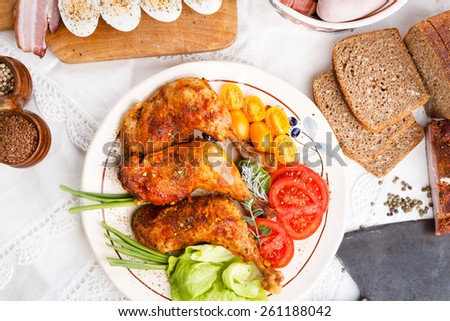 Roasted turkey legs with tomatoes and green salad and bred on white tablecloth