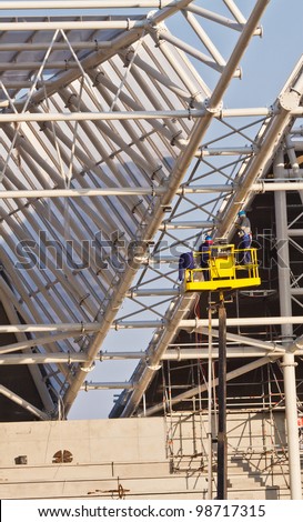 workers in air build grand stands construction of new stadium