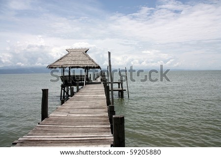 a wooden bridge leading to a wooden pavilion over the sea