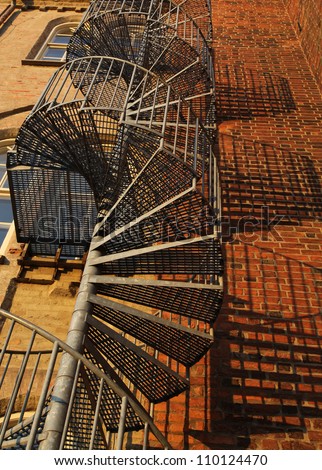 A winding spiral staircase used as fire escape in old gothic brick wall building.
