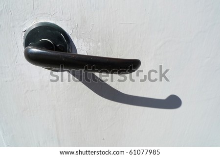 Closeup of a black door-handle against a white door. Gotland, Sweden.