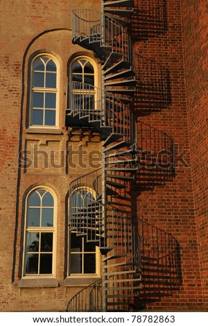 Spiral staircase and gothic windows on old brick wall.