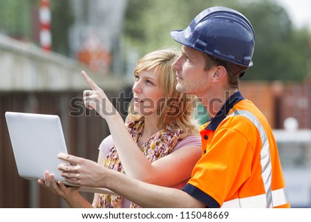 Businesswoman and construction worker with laptop discussing new project or working plan