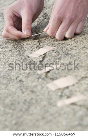 Man's hands applying adhesive bandage over cracks in the road. Vertical shot.