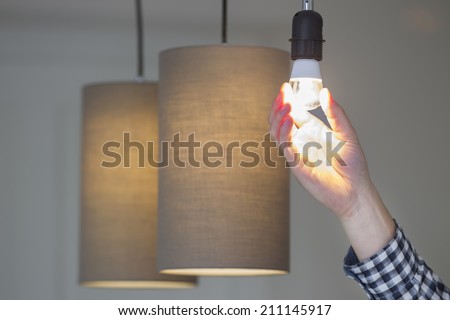 A man turning a lighted lightbulb in his own new house