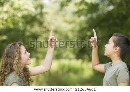 Two preteen girls pointing at copyspace