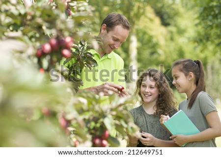 Pretty young girls having outdoor lesson  exploring nature in fruit orchard