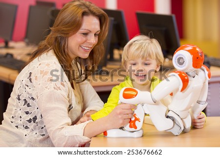 One young boy programming a robot with his science teacher on a primary school