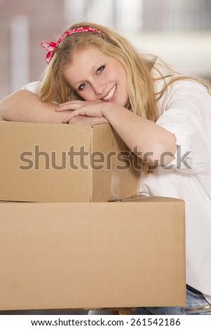 Pretty happy young woman moving in her new home unpacking boxes.