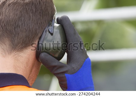 Closeup of construction worker wearing ear protectors at storage tank park