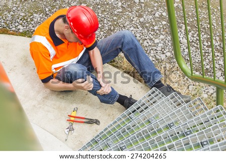 High angle view of mid adult worker suffering from leg pain by storage tank steps in park