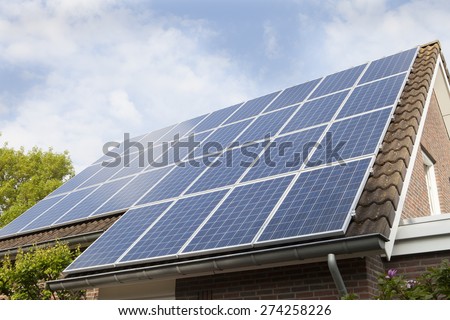 Low angle view of house roof covered with solar panels against sky