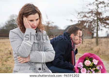 Upset woman thinking while sitting on bench with man