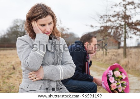Depressed woman thinking while sitting on bench with man
