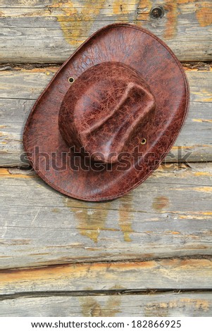 Leather hat, hanging wall of the wooden house. Texture, background