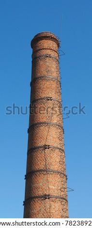 The old brick chimney with a ladder against the blue sky