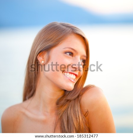 Outdoor portrait of beautiful happy girl looking over her shoulder, (shallow depth of field)
