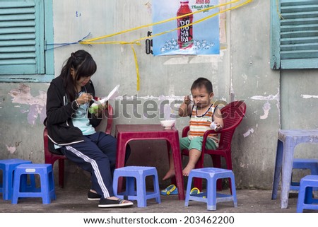 HO CHI MINH CITY,VIETNAM-NOV 5TH2013 : Young girl and boy eating breakfast at a street restaurant. Street restaurants are everywhere in Ho CHi Minh.