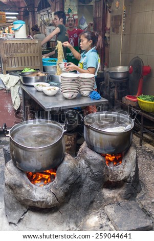 Bangkok, Thailand-Sep 28th 2012: A woman serves food from a street kitchen in Chinatown. There are many such kitchens in the area.