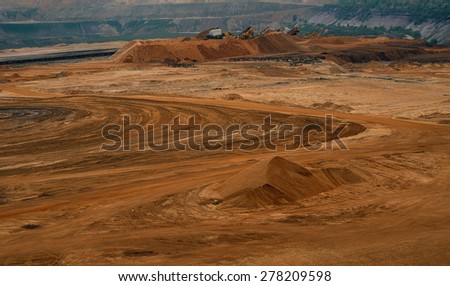 Sand quarry / Brown coal quarry / Bunk wall surface mine with exposed colored minerals and brown coal, mining equipment at the bottom the pit, view from above, top view