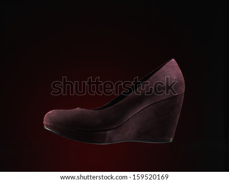 red suede shoes over dark red background