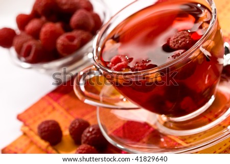 Cup of tea with raspberry syrup and some raspberries