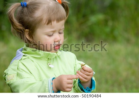 Little girl play with the tree twig in garden