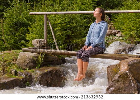 girl on a mountain river sitting on bridge