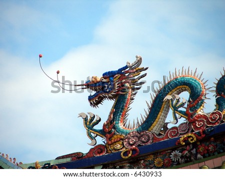Colorful Dragon on the roof of oriental temple, against blue sky