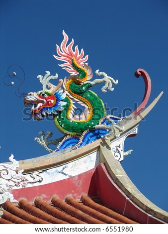 Beautiful Dragon on roof of oriental temple, against blue sky