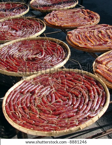 marinated Chinese sausage meat  drying on bamboo straw tray under the sun