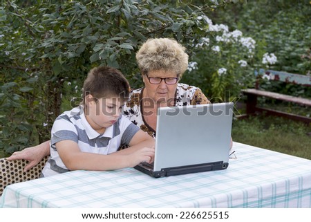 Granny with grandson behind the laptop outdoors