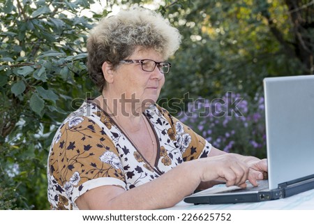 elderly woman working on  a computer in the garden